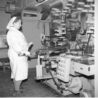 Kobieta podczas pracy przy maszynie napełniającej opakowania kosmetyków